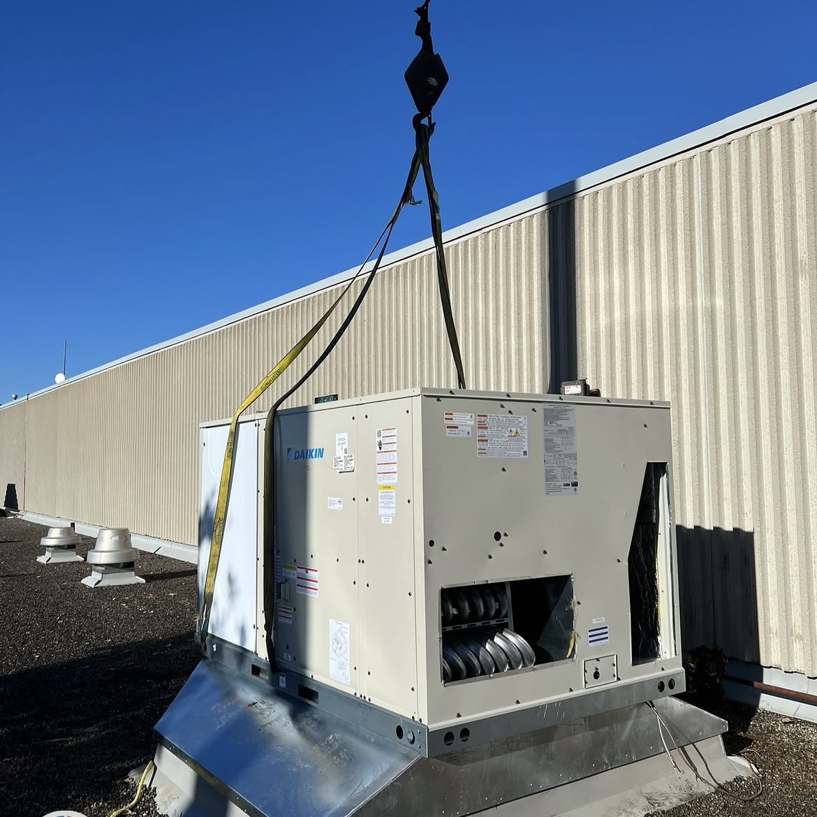 Commercial rooftop HVAC unit being lifted into place